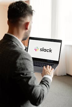 A business professional using Slack on a laptop indoors, highlighting modern communication technology.