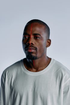 A portrait of a man in a white T-shirt with a red scanning line on his face, depicting advanced technology.