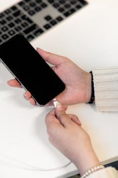 Close-up of hands plugging smartphone into charger, showcasing technology and connectivity.