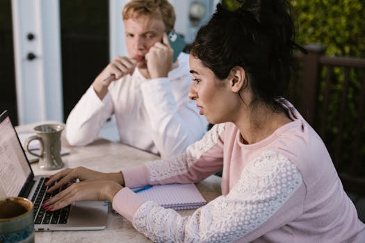 Two people working from home, one on a laptop and the other on a phone call, in an outdoor setting.